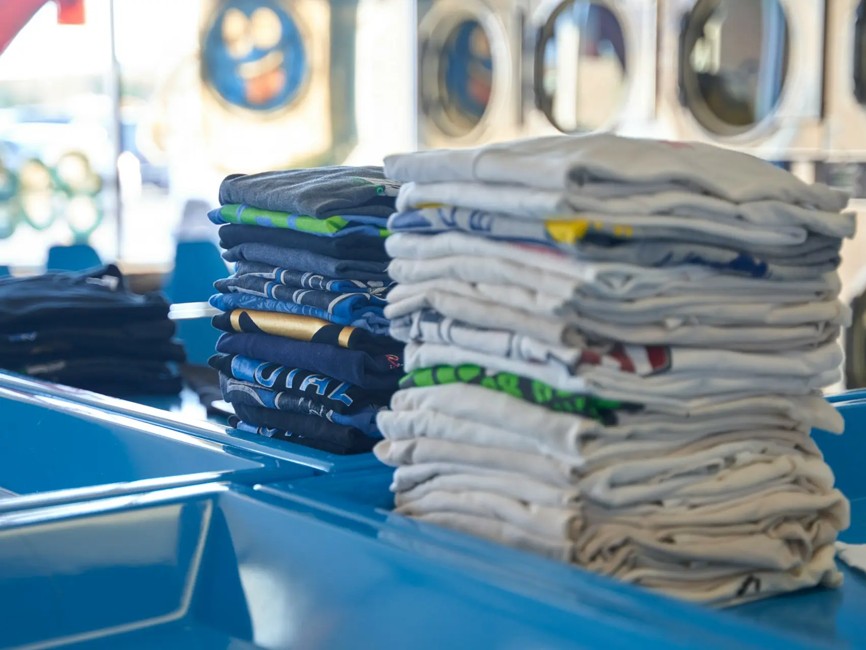 a stack of folded shirts sitting on top of a blue table